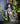 Statue of a ghostly witch figure with a moon and star headpiece on a shelf with books and plants.