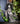 Statue of a ghostly witch figure with a moon and star headpiece on a shelf with books and plants.