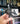 Hand holding a black figurine of a ghost witch with a cat on a bookshelf background