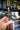 Hand holding a black figurine of a ghost witch with a cat on a bookshelf background